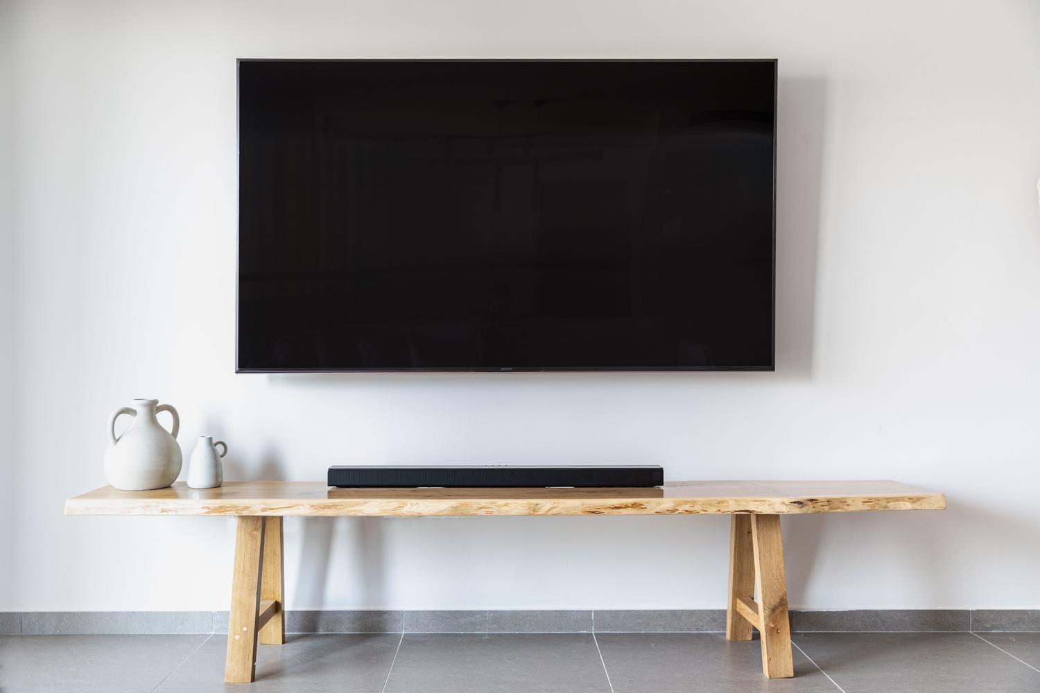 Salón moderno y minimalista con un televisor de pantalla plana montado en la pared y una barra de sonido integrada en el mueble.