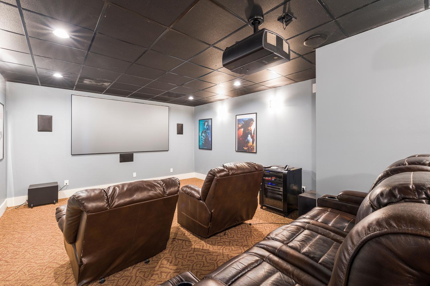 Instalación completa de cine en casa con asientos reclinables de cuero y un sistema de sonido envolvente profesional.