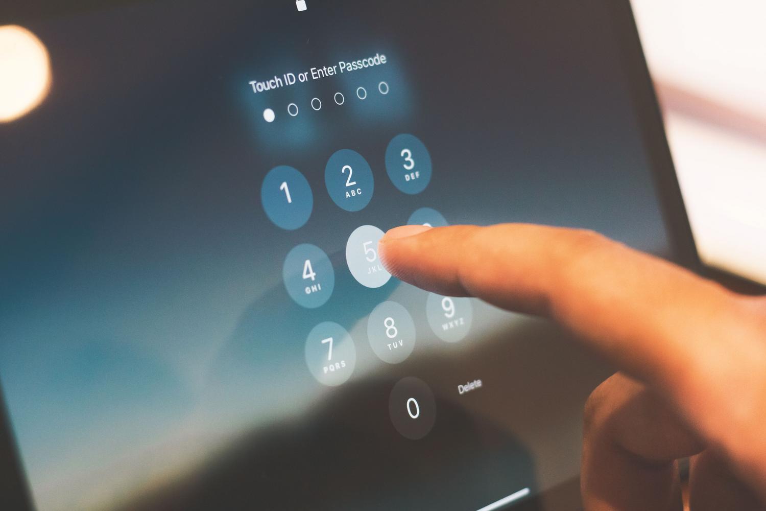 Dedo pulsando un código de acceso en la pantalla de bloqueo de un smartphone, representando la verificación de identidad y el uso de PIN de seguridad.