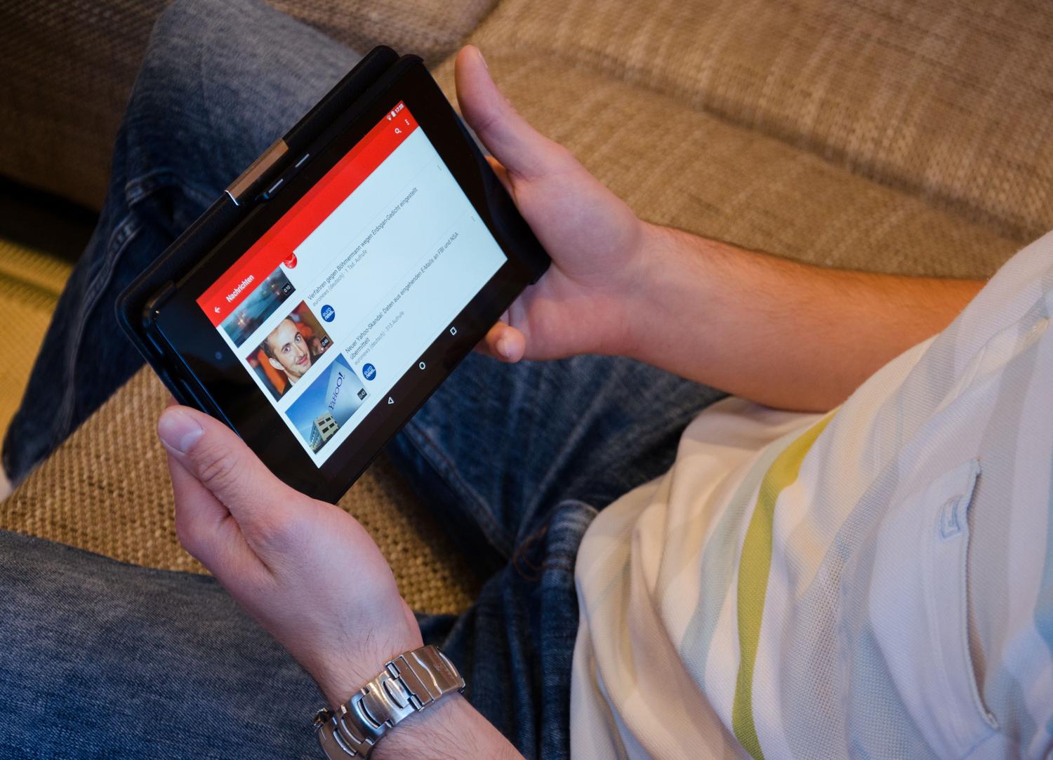 Hombre utilizando una tablet para ver contenidos de televisión a través de una aplicación de streaming, ilustrando la visualización de canales regionales por internet.