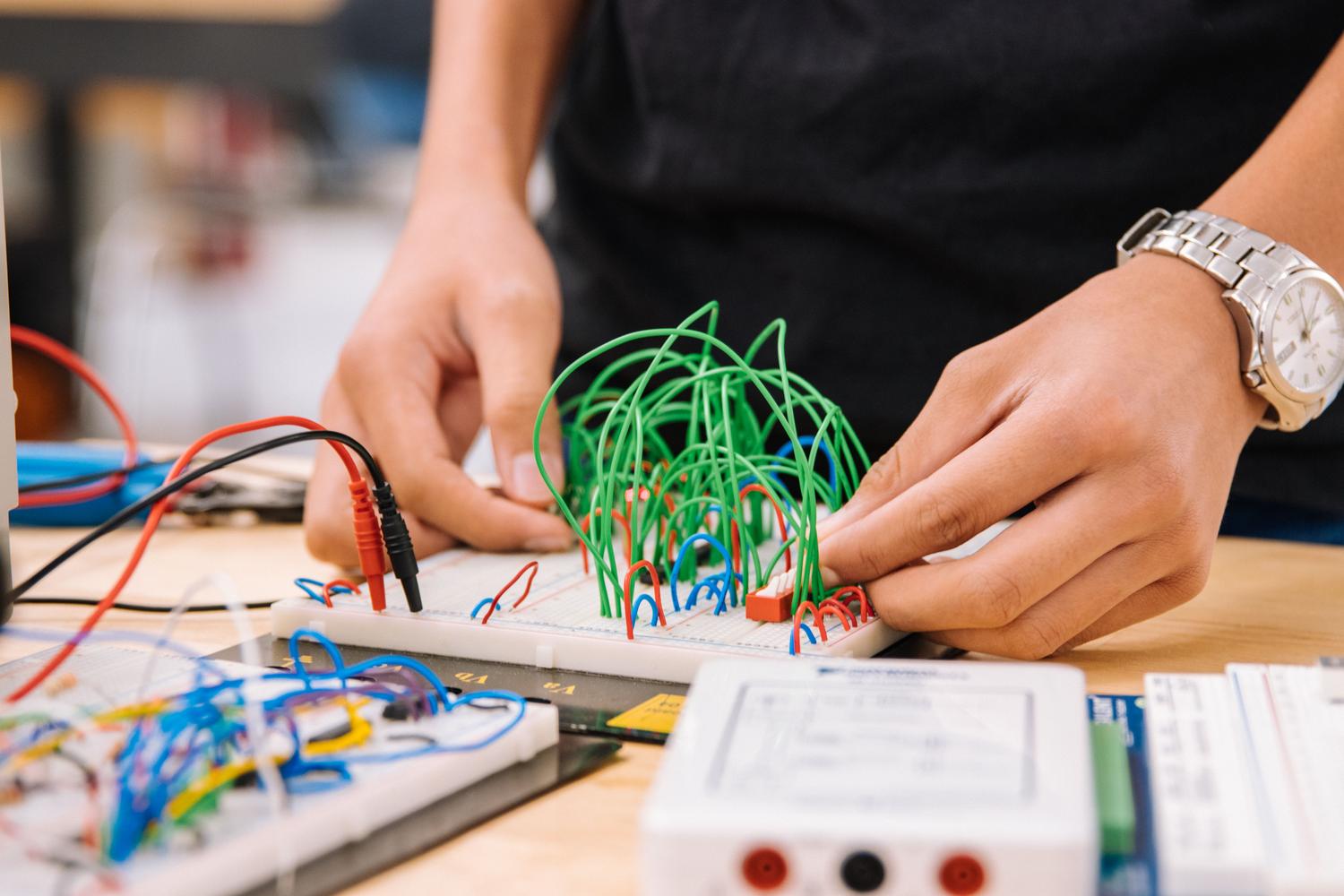 Manos de un ingeniero trabajando con cables puente sobre protoboards, ilustrando la fase de diseño y conexión de buses de comunicación en hardware. Manos de un ingeniero trabajando con cables puente sobre protoboards, ilustrando la fase de diseño y conexión de buses de comunicación en hardware.