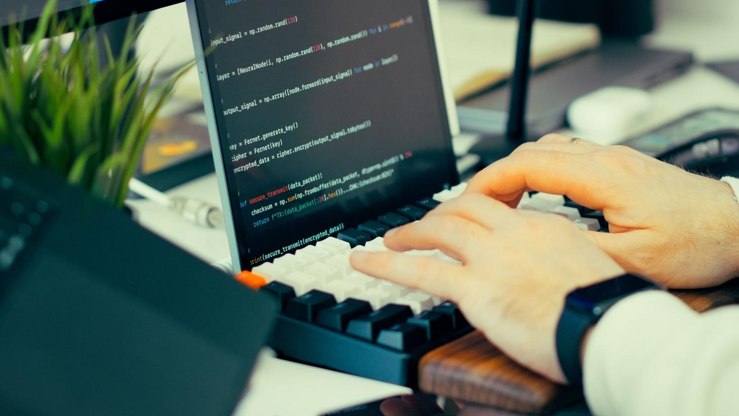 Desarrollador escribiendo código en el teclado frente a una pantalla con terminal, simbolizando la gestión de recursos en Linux.