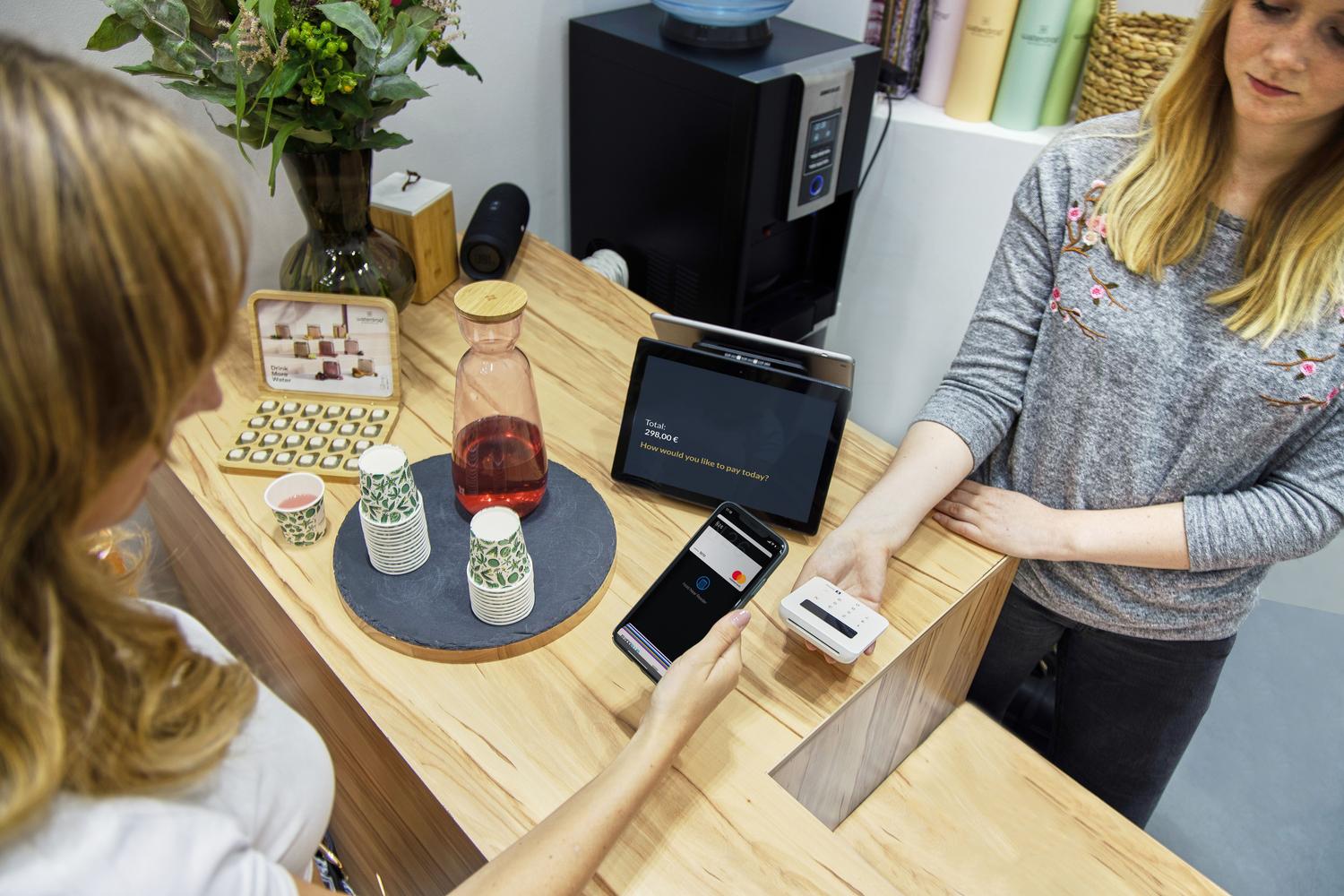 Mujer realizando un pago sin contacto con su smartphone en una cafetería moderna