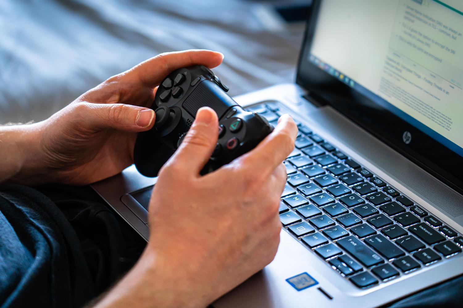 Persona interactuando con un ordenador portátil y un mando, mostrando que el juego es accesible desde diversos dispositivos.