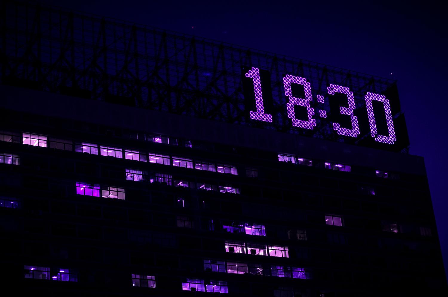 Reloj digital luminoso en un edificio moderno, representando el concepto de precisión horaria y el tiempo UTC.