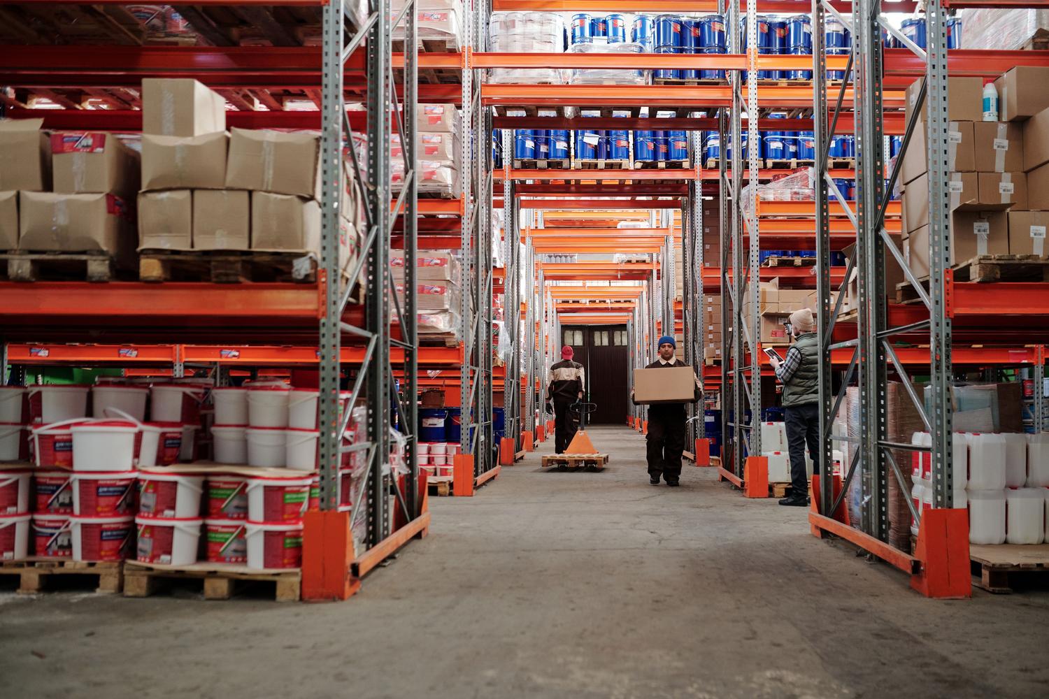 Trabajadores gestionando el inventario en un almacén industrial organizado, representando la operatividad y el flujo de trabajo logístico.