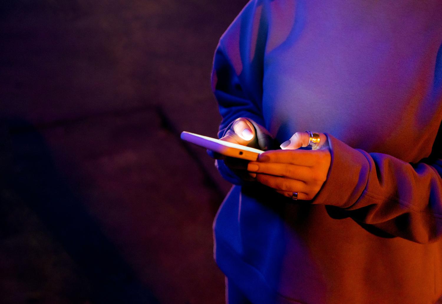 Persona interactuando con su teléfono móvil durante la noche