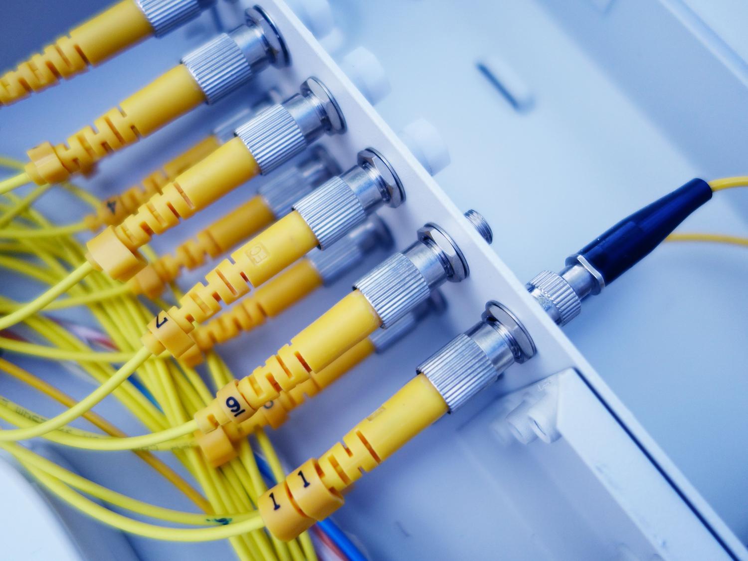 Primer plano de cables de fibra óptica amarillos en un servidor, ilustrando la transferencia de datos a alta velocidad en redes IoT.
