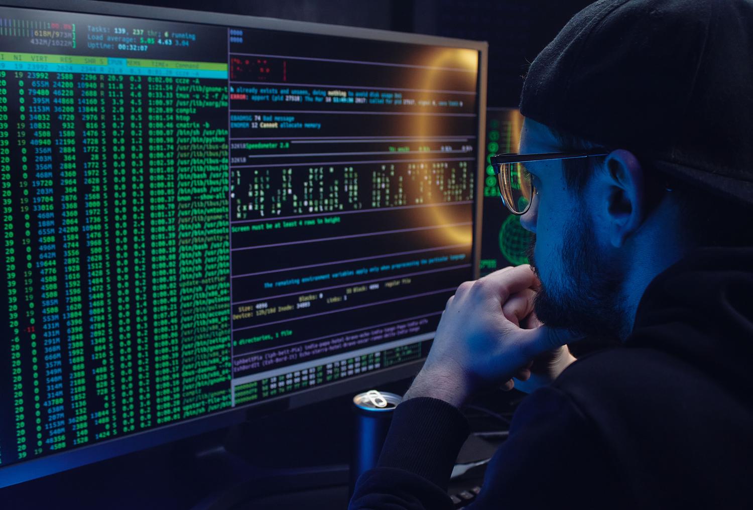 Profesional técnico trabajando con terminales de código en monitores duales, representando la base técnica necesaria para las certificaciones de ISC2.