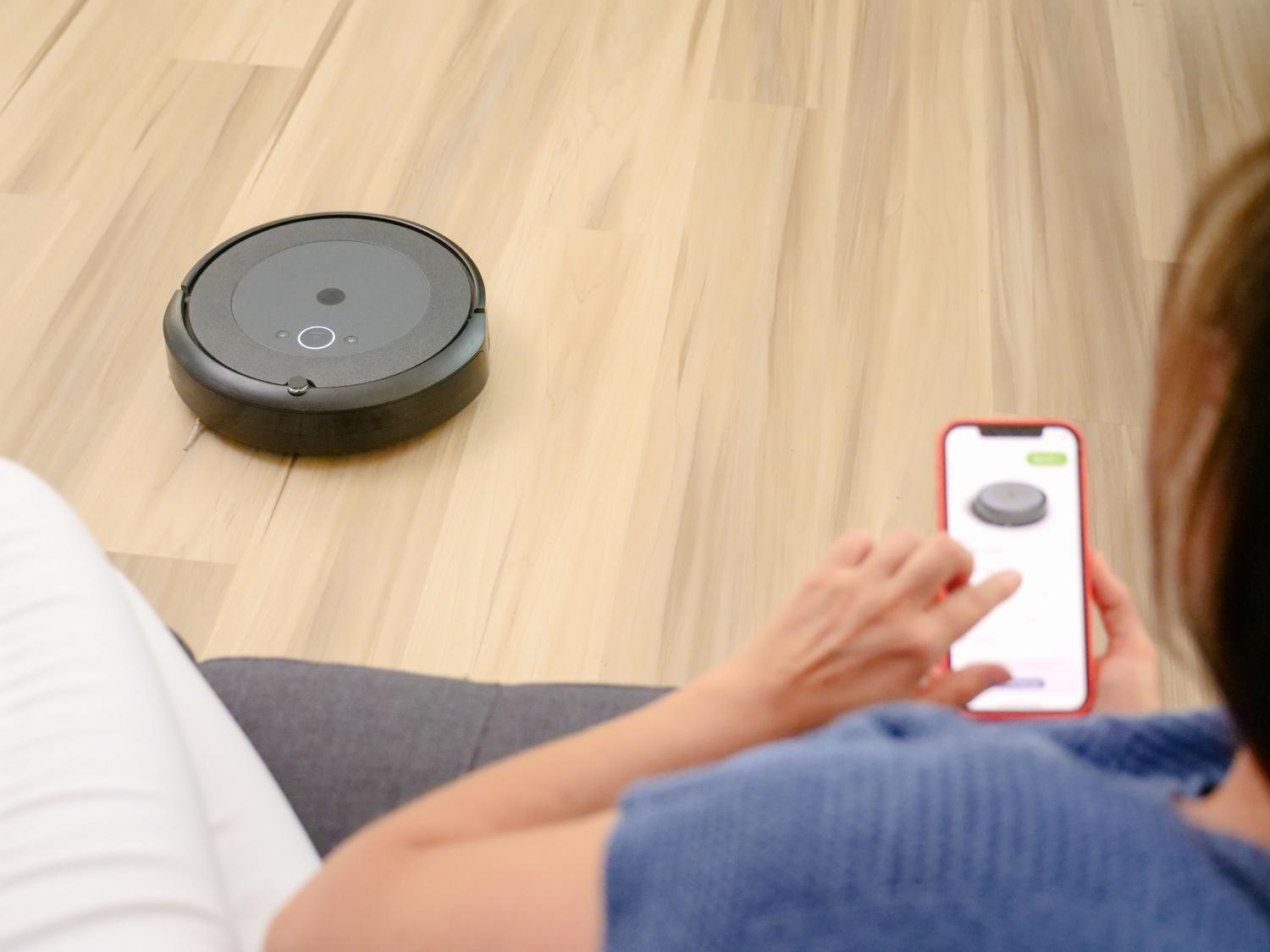Persona controlando un robot aspirador a través de una aplicación móvil en un smartphone