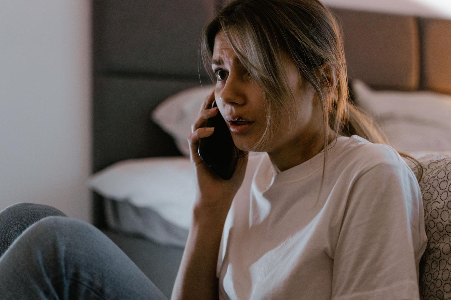 Mujer con expresión preocupada realizando una llamada telefónica urgente, ilustrando la presión psicológica de las estafas.