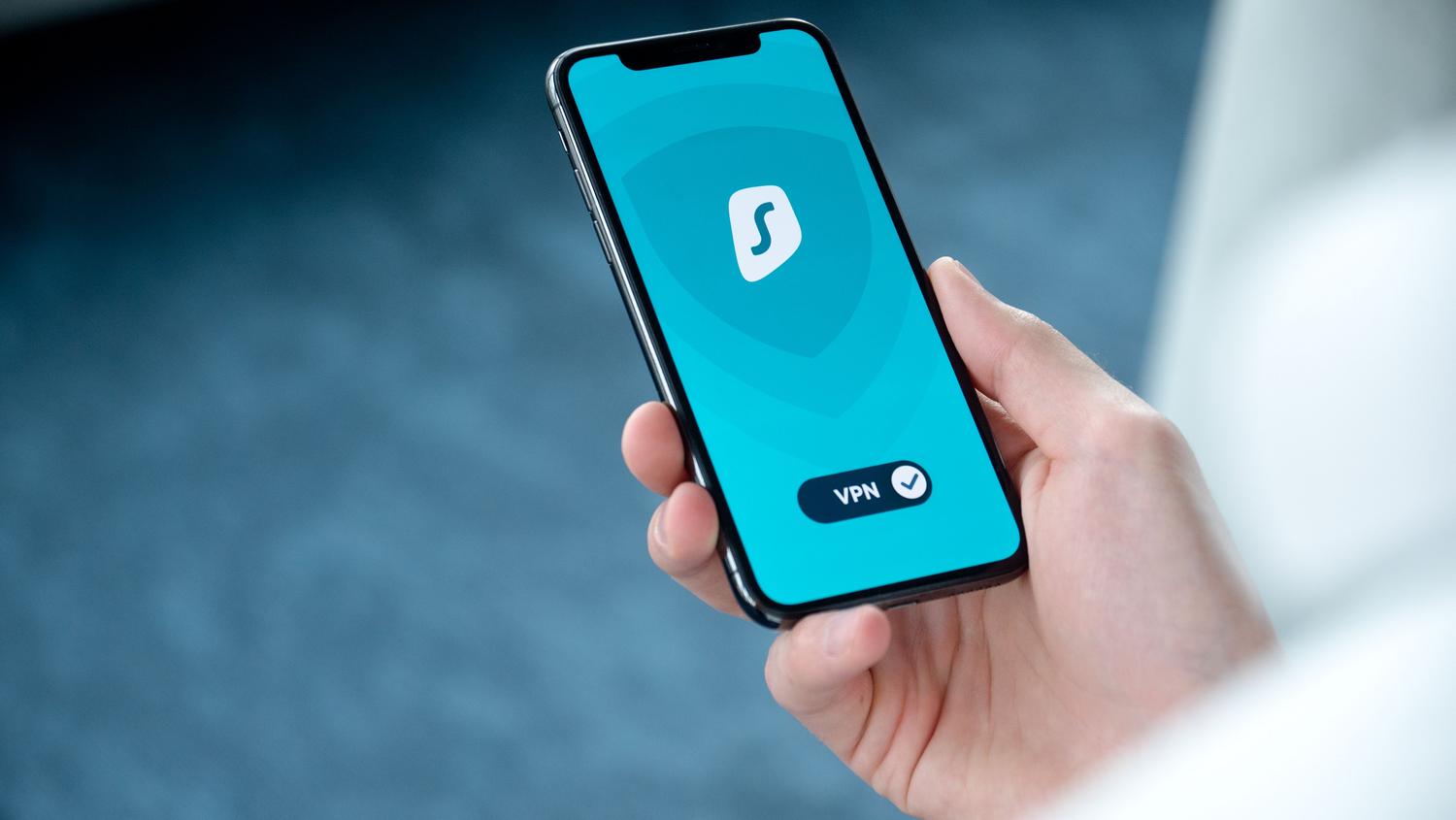 Mano sosteniendo un smartphone con una aplicación de seguridad y VPN activada, ilustrando la protección de datos móviles.