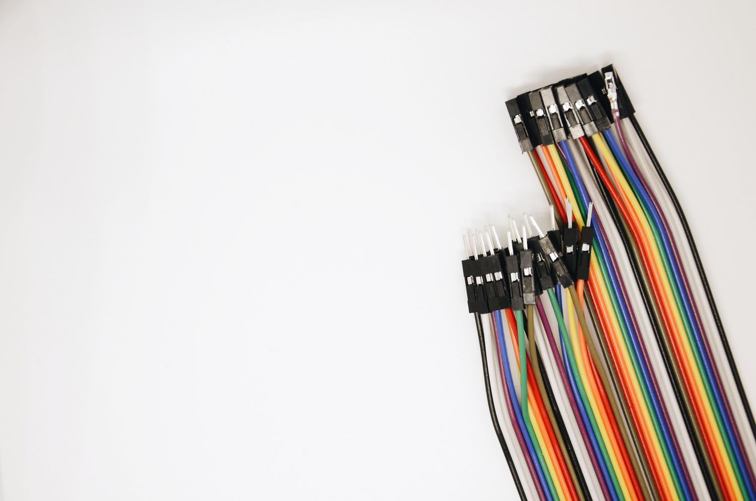 Cables puente para el bus I2C Conjunto de cables puente (jumper wires) multicolores, representando la simplicidad del cableado de dos hilos (SDA y SCL) característico del bus I2C.