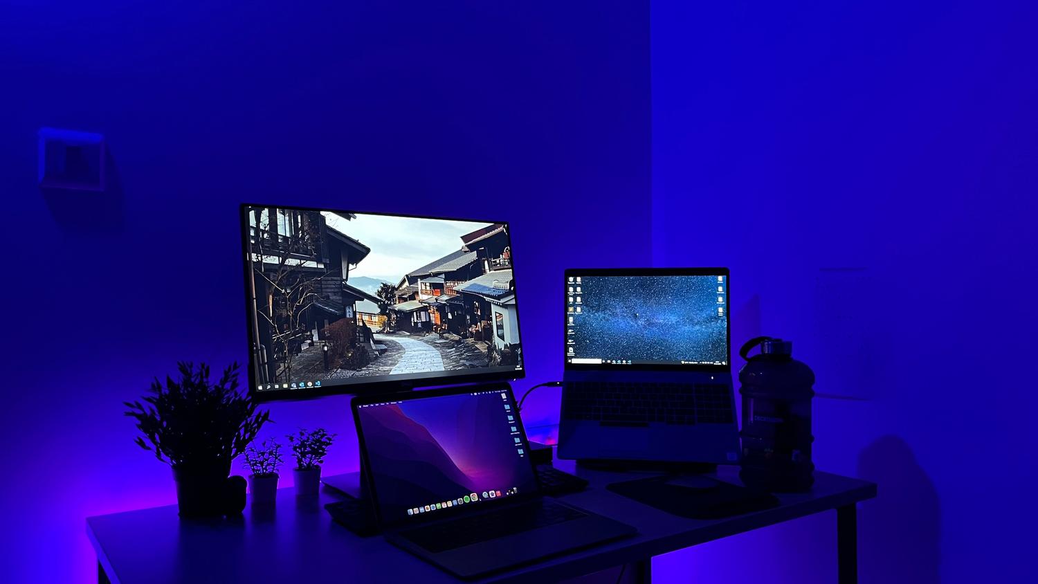 Configuración de ordenador gaming de alta gama con múltiples monitores e iluminación LED azul, ideal para el metaverso.
