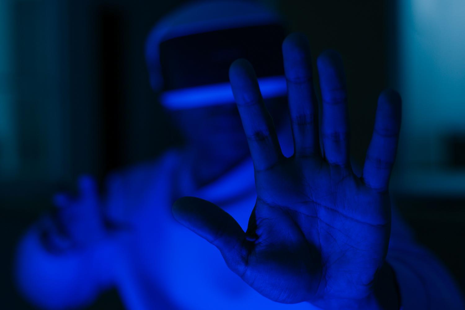 Primer plano de una mano interactuando con interfaces invisibles en un entorno ciberespacial iluminado en azul.