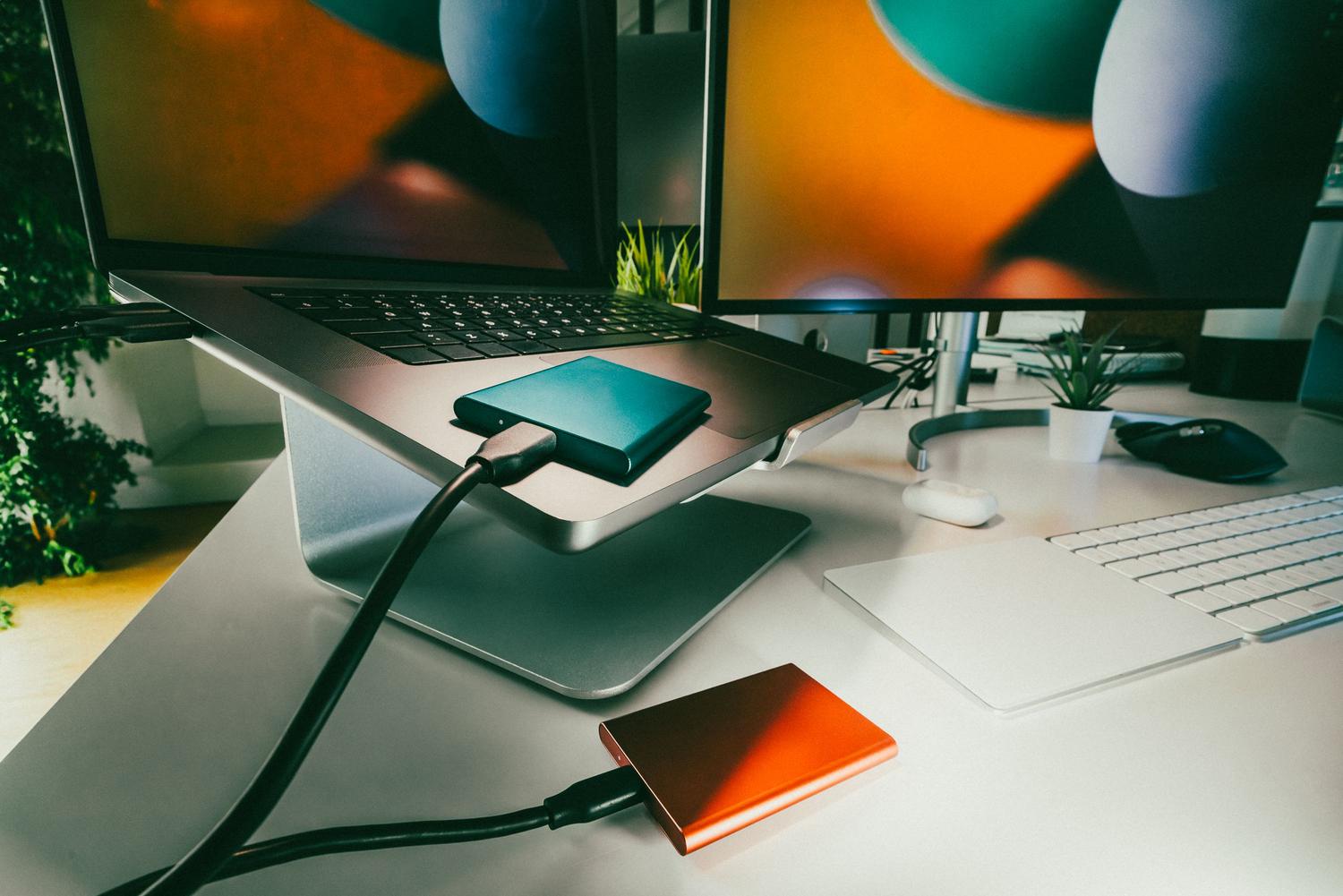 Espacio de trabajo moderno con laptop y discos duros externos conectados para realizar copias de seguridad.