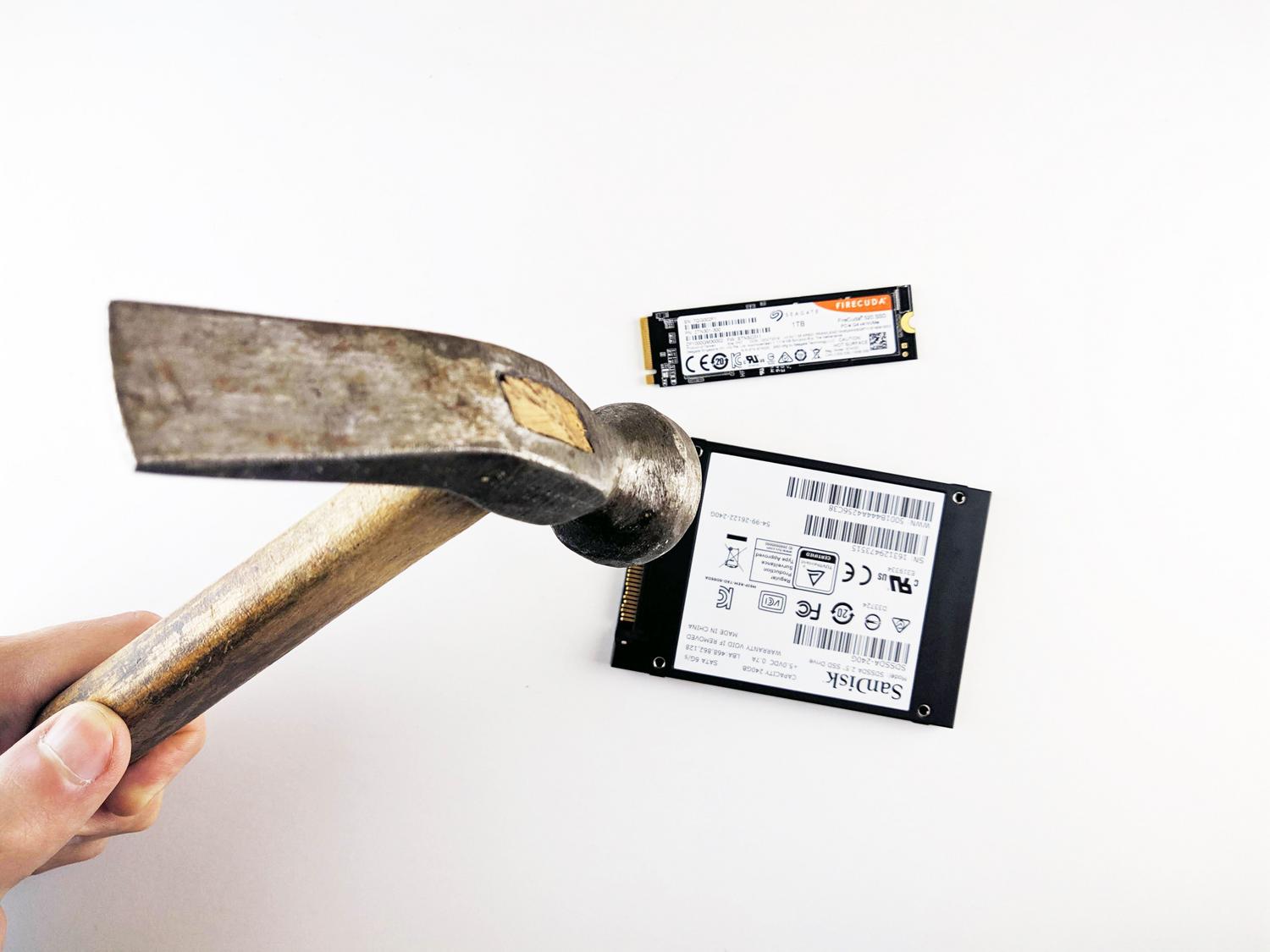 Un martillo a punto de golpear unidades SSD, simbolizando la destrucción física total y la imposibilidad de recuperar los datos.