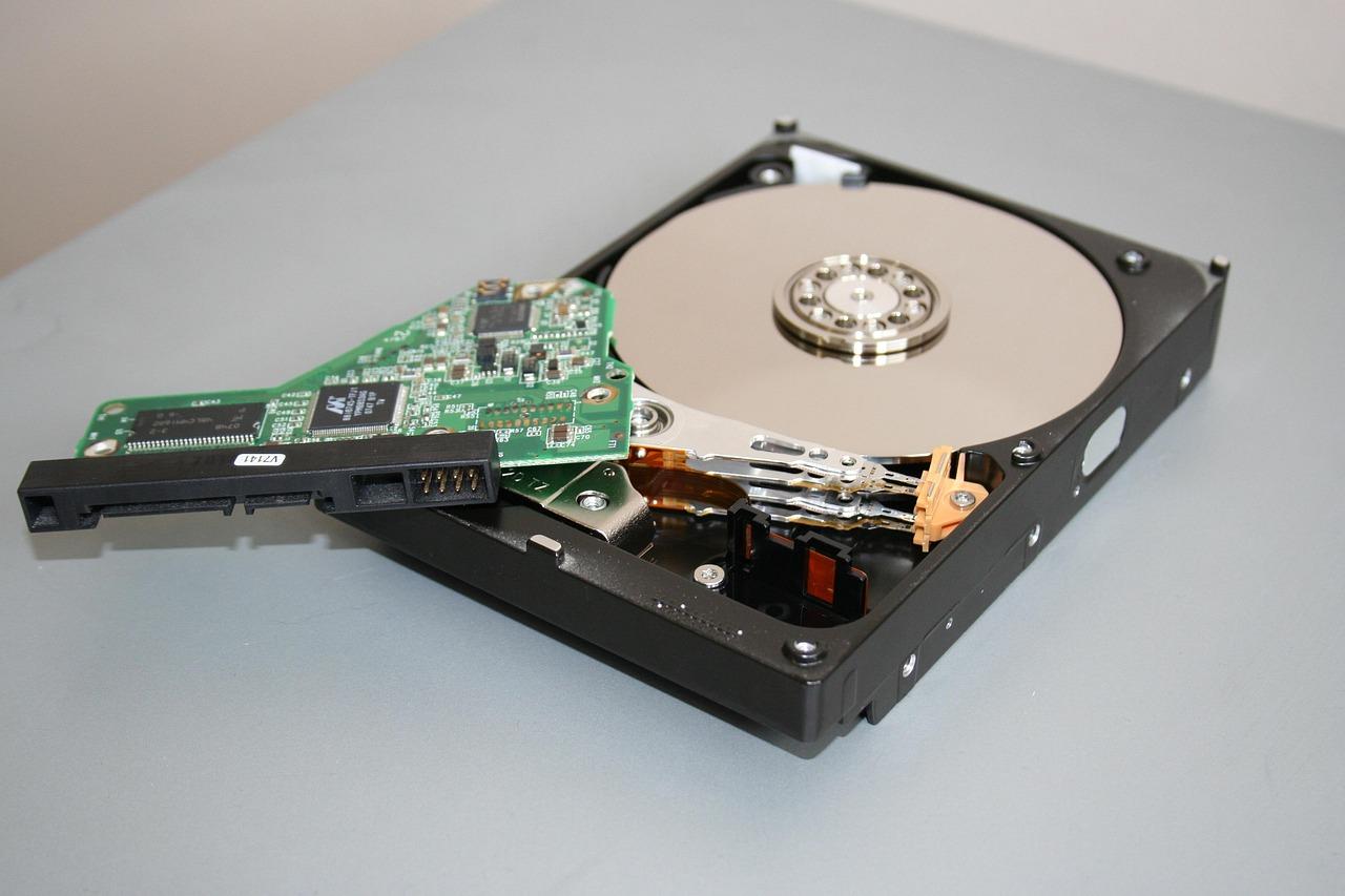Disco duro abierto con componentes expuestos, representando un fallo de hardware y el proceso de recuperación de datos.