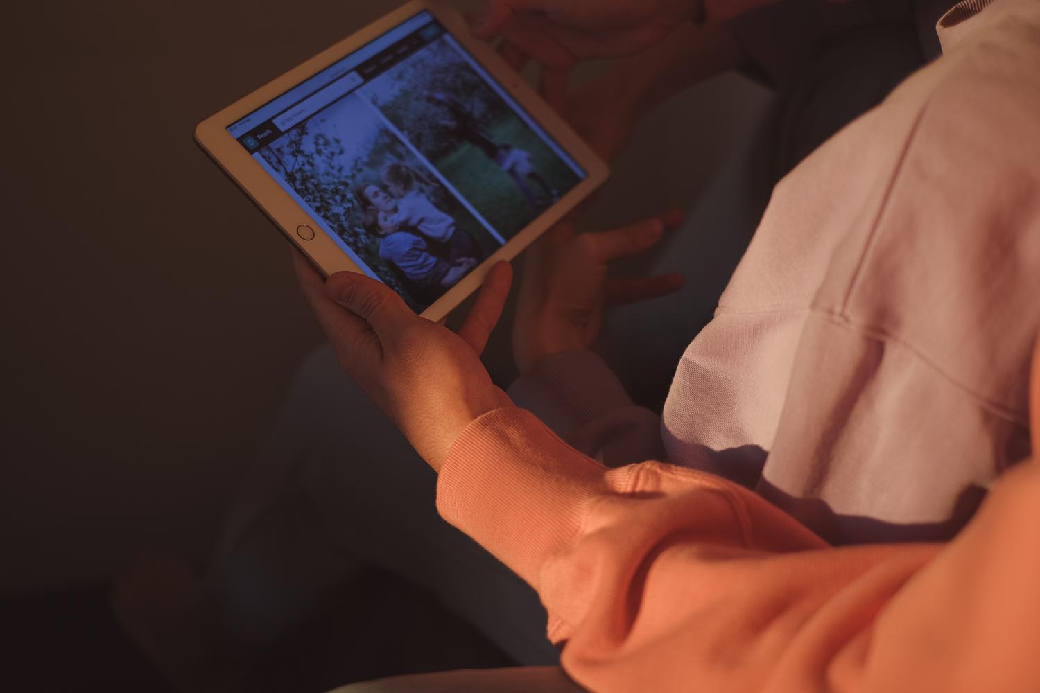Manos revisando fotografías en una tablet buscando archivos perdidos