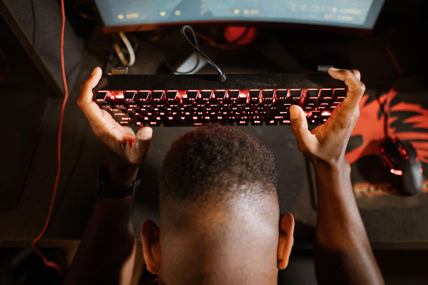 Frustrated gamer holding a mechanical keyboard, representing the annoyance of FPS drops and lag caused by high CPU usage.