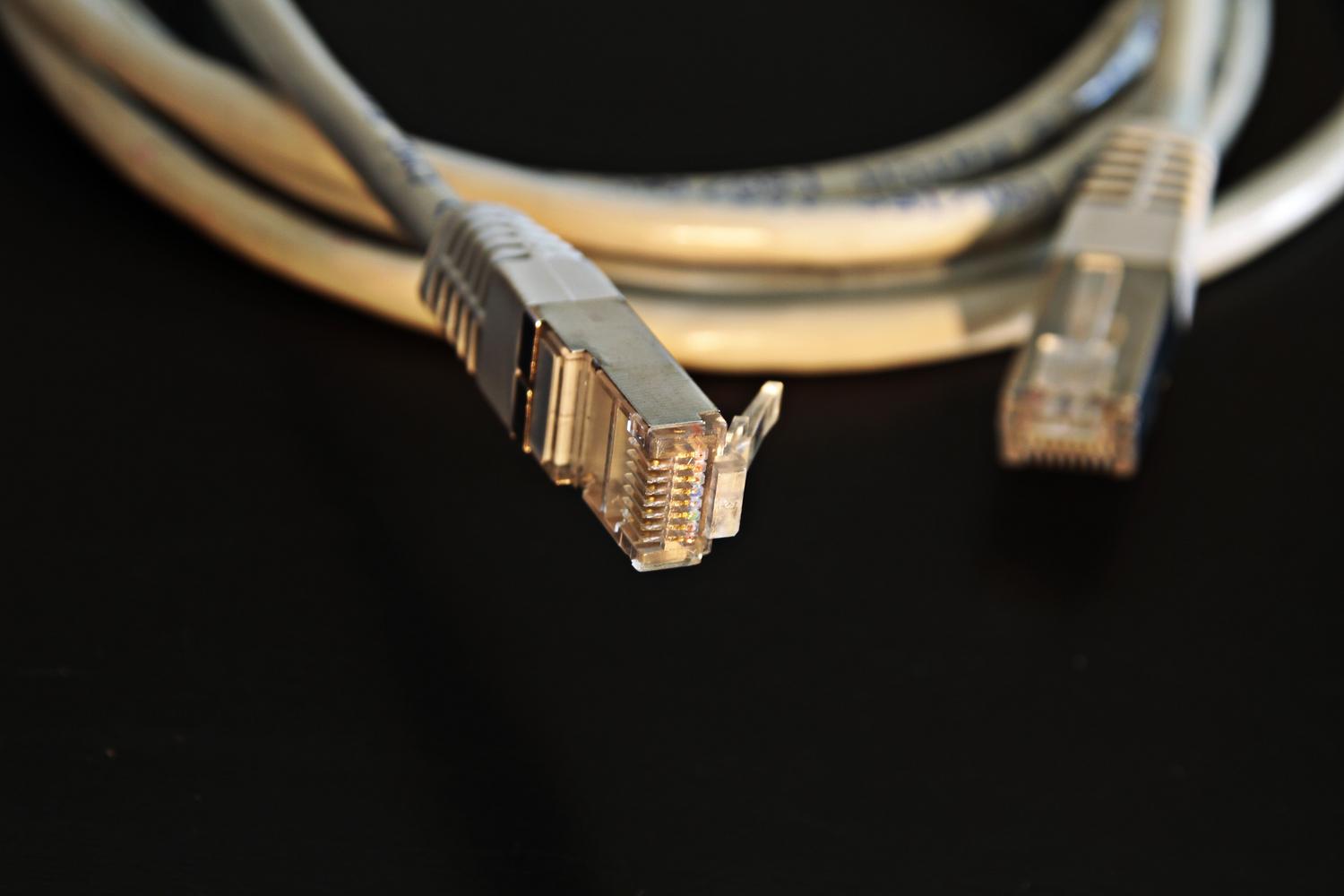 Detalle macro de un conector RJ45 con blindaje metálico, representando el cableado de alta calidad Cat 6A o Cat 7 necesario para 10Gbps.
