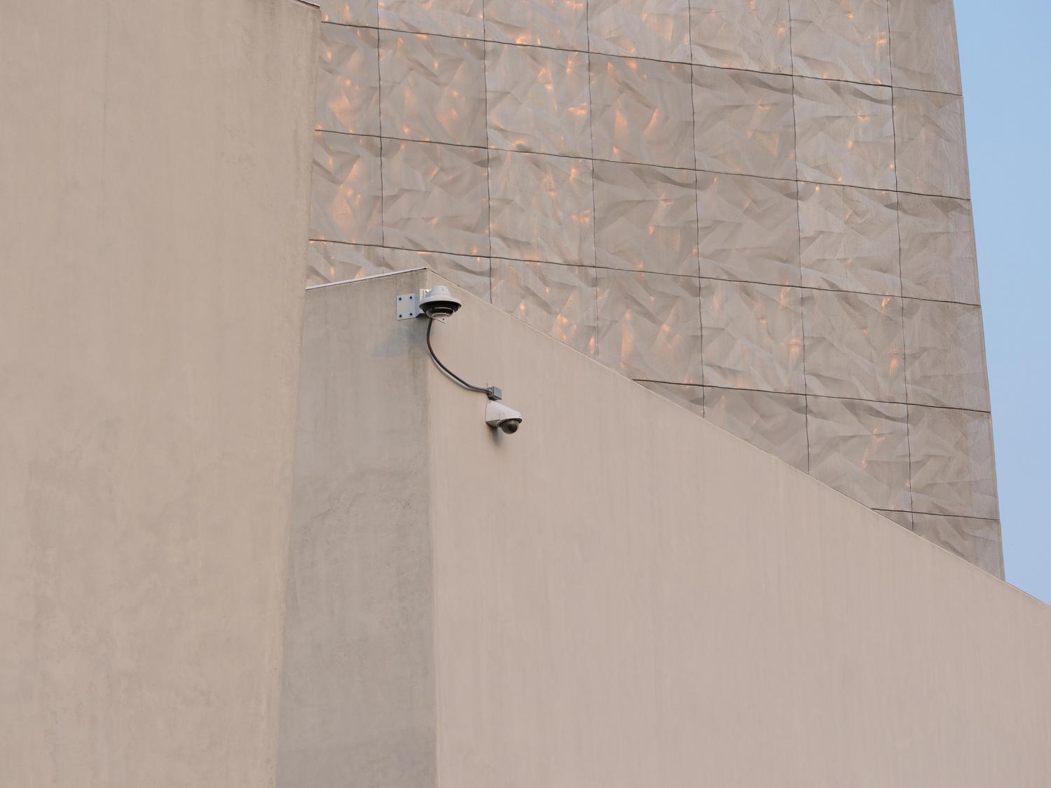 Instalación de cámaras de vigilancia en la fachada de un edificio moderno, destacando la seguridad en exteriores.