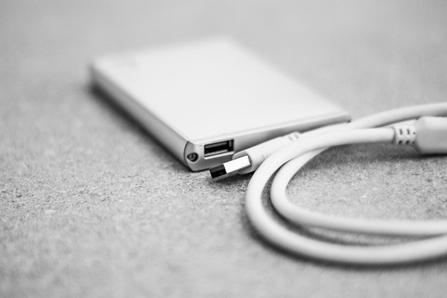Fotografía artística en blanco y negro de un disco duro externo con un cable USB, simbolizando un proceso de formateo interrumpido o atascado.